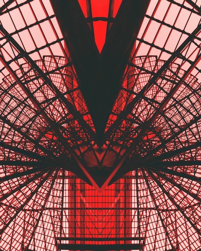 Abstract view of a red geometric architectural structure, showcasing modern design and symmetry.
